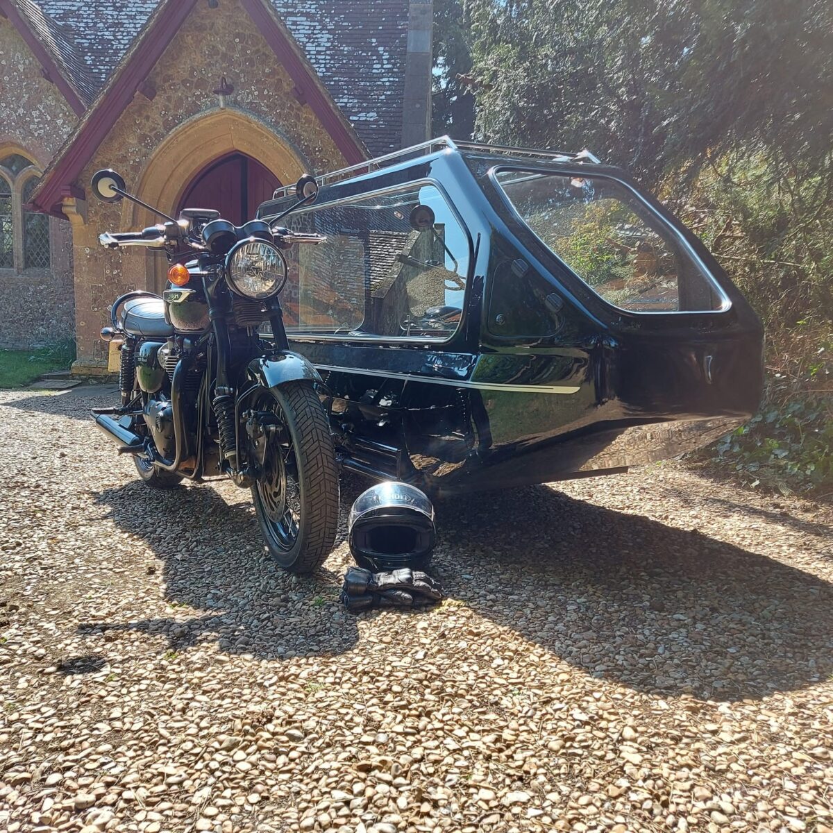 Black Triumph Bonneville Bike with side hearse outside church